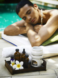 Shirtless man lying on poolside