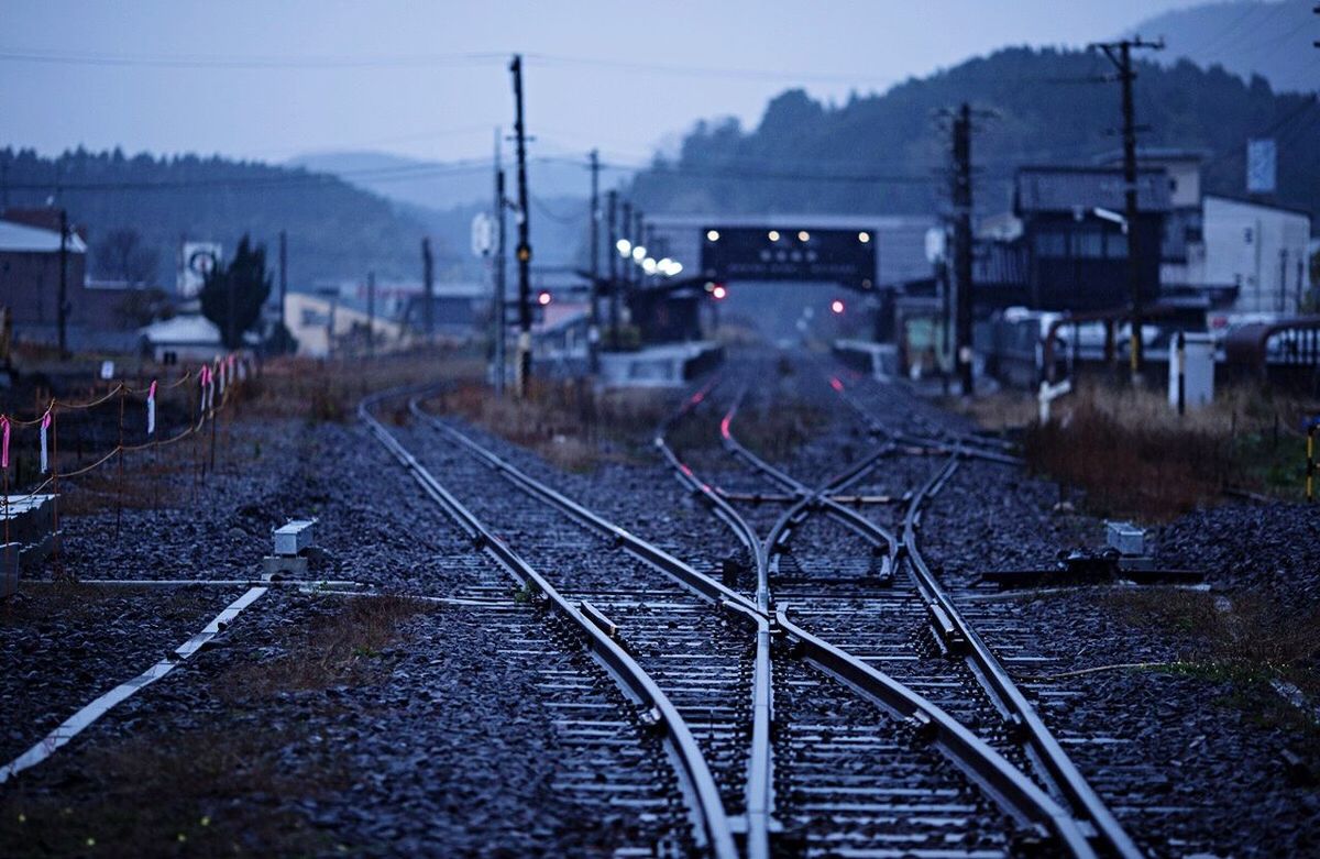 railroad track, building exterior, transportation, rail transportation, built structure, sky, electricity pylon, architecture, power line, public transportation, dusk, outdoors, no people, electricity, mode of transport, city, house, railway track, nature, cable