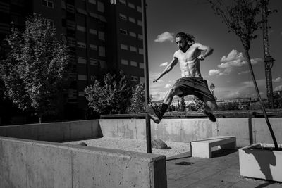 Shirtless man jumping on railing in city