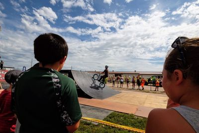 Rear view of people on shore against sky