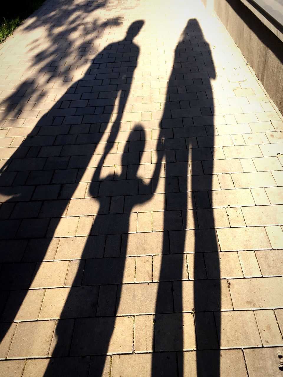 HIGH ANGLE VIEW OF PEOPLE SHADOW ON COBBLESTONE