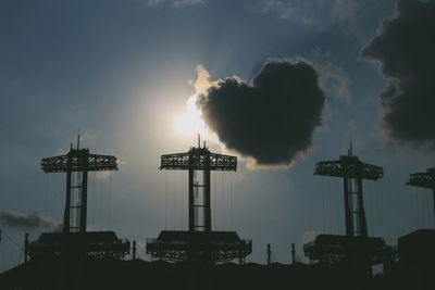 Low angle view of silhouette cranes against sky at sunset