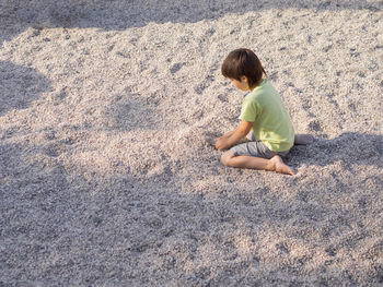 Boy is playing with gravel on modern children's playground. developing fine motor skills