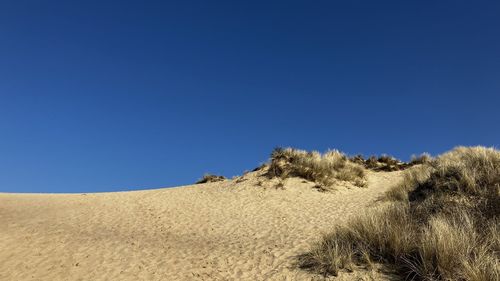 Scenic view of desert against clear blue sky