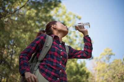 Low angle view of woman drinking water against sky