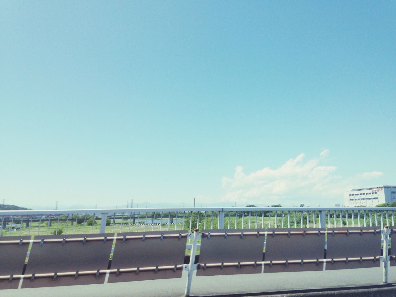 railing, copy space, sky, clear sky, blue, full length, fence, lifestyles, leisure activity, day, built structure, road, outdoors, sunlight, walking, rear view, transportation, standing