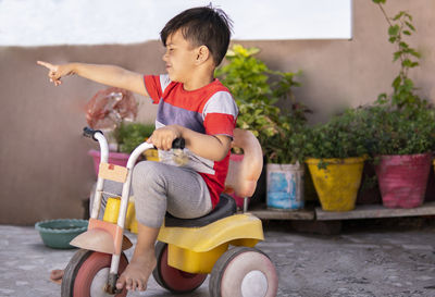 Full length of boy sitting in tricycle outdoors