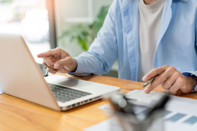 Midsection of man using laptop on table