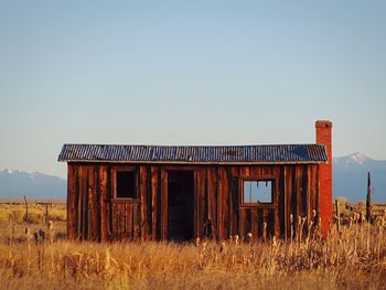 Abandoned barn on field against clear sky