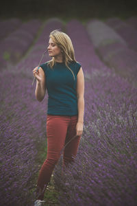 Young woman standing amidst flowering plants on field