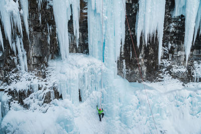 Male ice-climber scaling a massive and treacherous ice wall. 