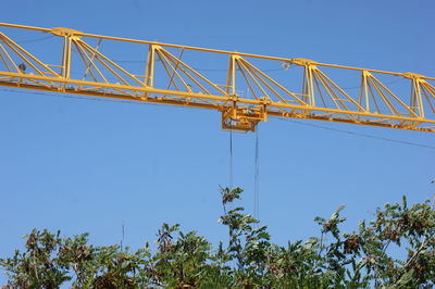 Low angle view of crane against clear blue sky