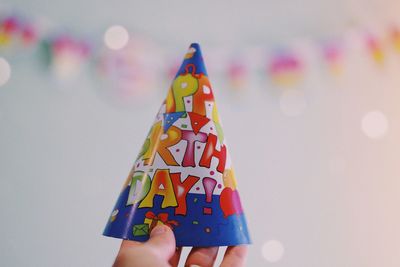 Cropped hand of person holding birthday cap at home