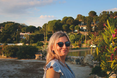 Portrait of young woman wearing sunglasses against sky