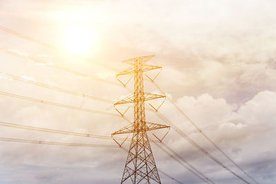 Low angle view of electricity pylon against cloudy sky