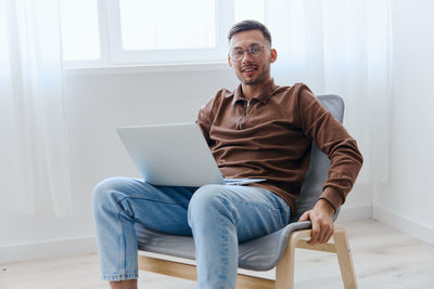 Young woman using laptop while sitting on sofa at home