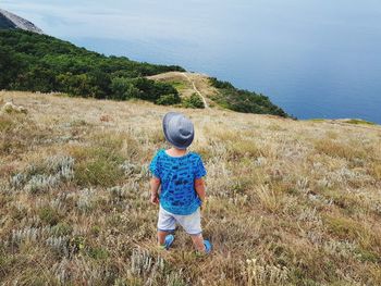 Full length rear view of boy on sea shore