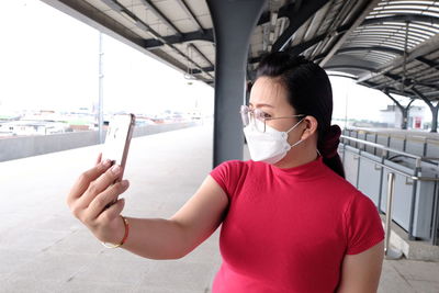 Asian woman taking a selfie at a train station