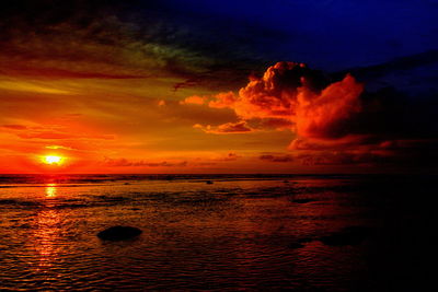 Scenic view of sea against dramatic sky during sunset