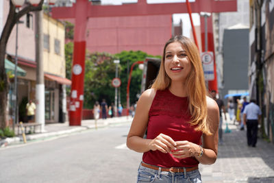 Portrait of beautiful cheerful young woman walking in street of asian neighborhood in the city