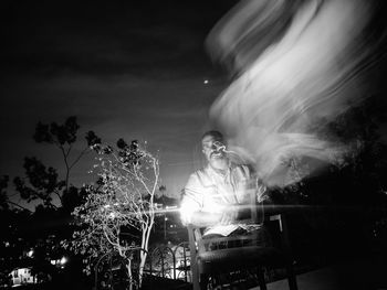 Portrait of man sitting on chair against sky at night