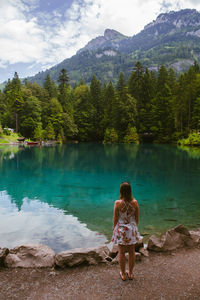 Rear view of woman standing by lake against sky