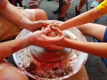 Midsection of women shaping pottery in city