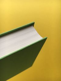 Close-up of green book on yellow background