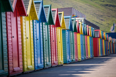 Multi colored umbrellas on beach huts against buildings