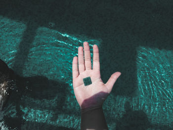 Close-up of hand touching water in swimming pool