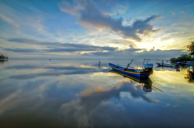 Boat moored in sea against sky during sunset