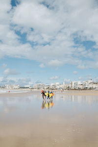 People on beach against sky in city