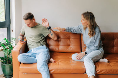 A man uses a mobile phone and ignores his wife who wants to talk about problems