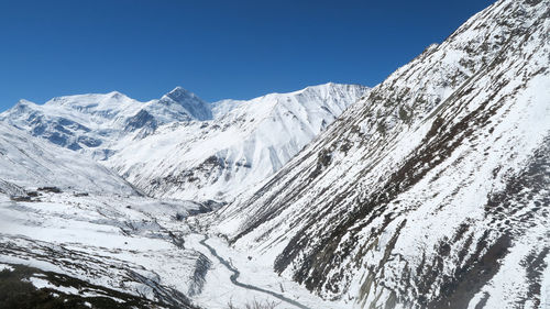 Scenic view of snowcapped mountains against clear blue sky