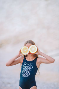 Girl holding fruits standing on beach