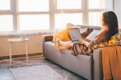 Young woman sitting on sofa at home