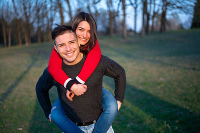 Portrait of smiling young woman standing against trees