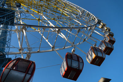 Low angle view of ferris wheel against clear blue sky