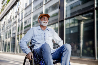 Smiling senior man sitting in wheelchair on footpath