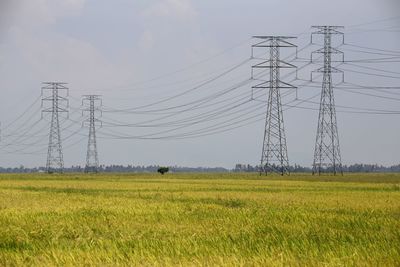 Electricity pylon on field against sky