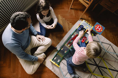 High angle view of father and daughters with toy cars at home