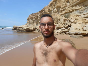 Portrait of shirtless young man standing at beach