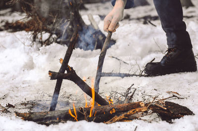 Low section of man burning campfire during winter