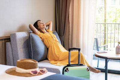 Full length of woman sitting on sofa