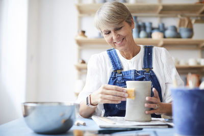 Smiling mature woman learning pottery in art class