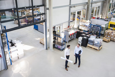 Two businessmen talking in factory shop floor