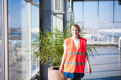 Portrait of woman in reflective clothing standing by wall