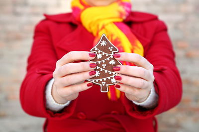 Midsection of woman holding gingerbread cookie during christmas