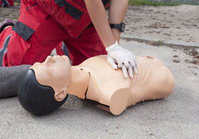 Midsection of paramedic performing cpr on mannequin