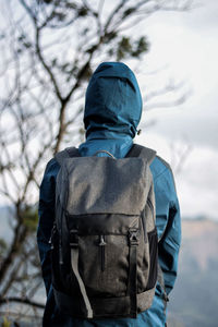 Rear view of man wearing hood against tree during winter